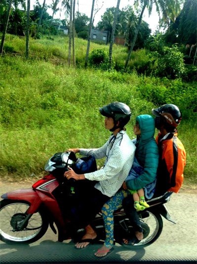 Trys berniukai važiuojantys ant vieno motorolerio Vietname